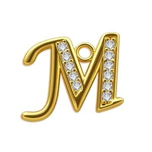 Detailaufnahme des goldenen M-Anhängers mit Zirkonia-Steinen, glänzendes Schmuckaccessoire.