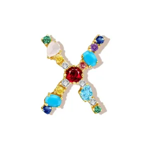 Detail view of a colorful cubic zirconia letter X pendant accessory in gold-plated copper.
