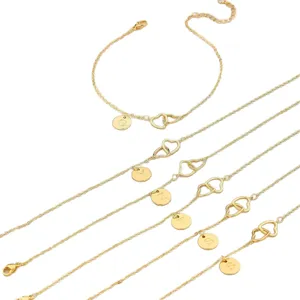 Dettaglio di bracciali dorati con cuori intrecciati e ciondoli con lettere incise.