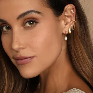 Close-up detail shot of women gold earrings set featuring pearl drop hoop and cartilage ear cuffs.