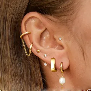 Gold-plated ear cuff and stud earring set detail showcasing sparkling zirconia and pearl charms.