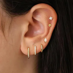 Detailed close-up view of trendy gold hoop earrings and shiny stud sets for multiple ear piercings.