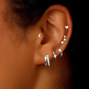 Close-up of multi-piece silver piercing earrings set featuring hoops and cute studs.