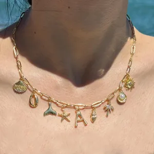 Primo piano della collana con ciondoli dorati e ciondoli da spiaggia estivi come conchiglie.