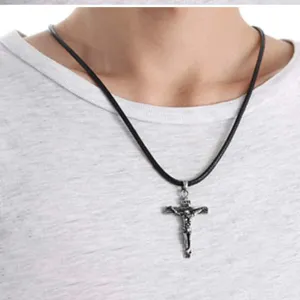 Primo piano dettagliato del ciondolo a croce in argento vintage su corda di cuoio nero.