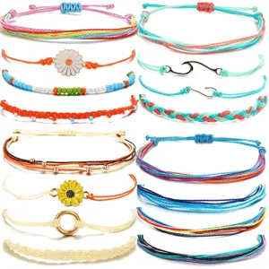 Close-up of handmade woven cord bracelets featuring colorful string, daisy charms and wave pendants.