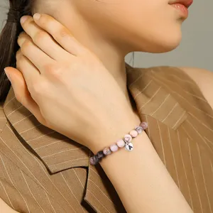 Bracelet de perles en pierre rose naturelle avec charm cœur lettre porté au poignet mannequin