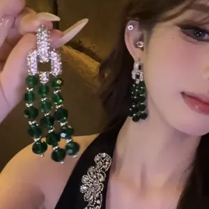Gedetailleerde close-up van luxe groene kristallen kwast oorbellen met sprankelende strass.