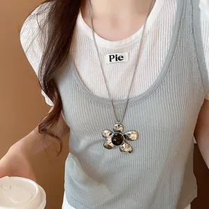 Dettaglio ravvicinato di collana con ciondolo a fiore in metallo argentato indossata.