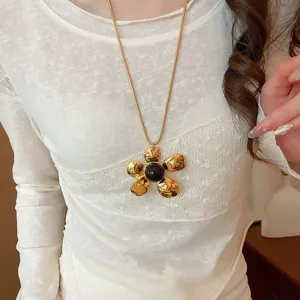 Collana con ciondolo a fiore in metallo dorato con centro scuro, elegante gioiello da clavicola.