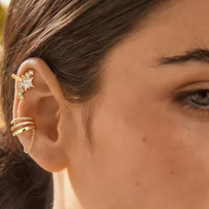 Detailed close-up of gold star ear cuffs and chain hoop set, modern fashion cartilage jewelry.