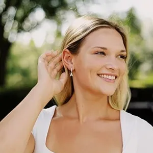Primo piano dettagliato degli orecchini pendenti con lettera minimalista indossati dalla modella.