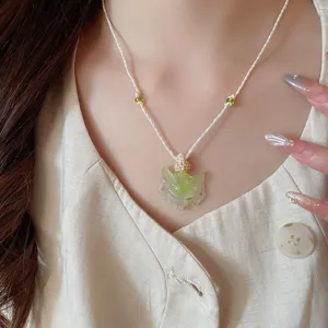 Primo piano della collana con ciondolo volpe in resina verde traslucida e corda bianca.