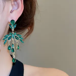 Gros plan sur les magnifiques boucles d'oreilles pendantes en cristal vert au design doré.