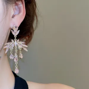 Gros plan de boucles d'oreilles pendantes en cristal rose, vue détaillée dorée scintillante.