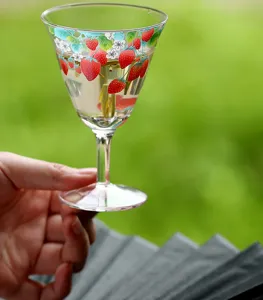 Close-up detail of the elegant glass teacup featuring charming strawberry and floral prints.