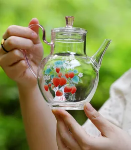 Close-up detail of the clear glass teapot featuring lovely strawberry print and pink handle.