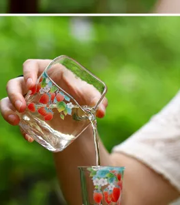 Détail de pichet à thé en verre transparent avec motif de fraise versant du thé frais.
