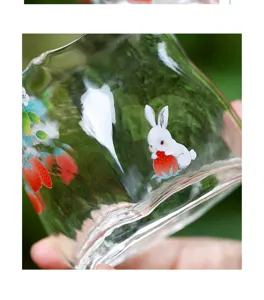 Gros plan détaillé de la tasse à thé en verre clair avec motif de lapin et de fraise.