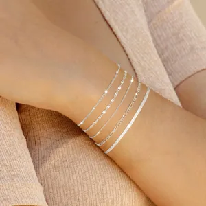 Detalle de elegantes pulseras plateadas en capas que muestran delicadas cadenas en la muñeca.