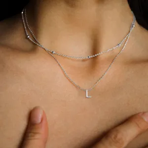 Vista dettagliata della collana doppia con iniziale e perline, gioiello in acciaio donna.
