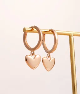 Primo piano di eleganti orecchini a cerchio con ciondolo a cuore placcato oro 14k finitura.