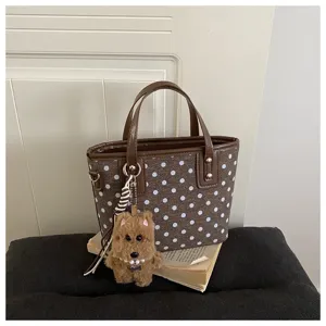 Detailansicht der braunen gepunkteten Ledereimer Tasche mit einem süßen flauschigen Hundeanhänger.