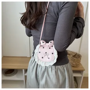 Detail shot of a cute pink polka dot mini crossbody bag featuring white lace trim and bow.