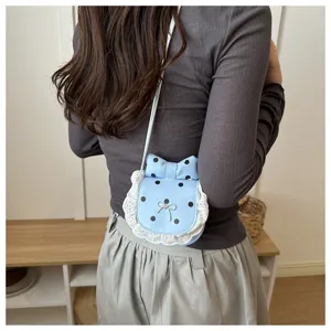 Detail view of the cute blue polka dot mini crossbody bag with sweet lace and bow design.