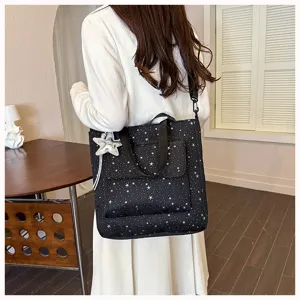 Black canvas tote bag with white star pattern, front pocket and shoulder strap detail.
