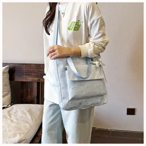 Detailed shot of a stylish light blue star print tote bag with front pocket and cute charm.