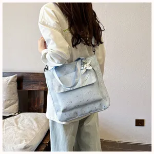 Detailed view of light blue tote bag with star pattern, shoulder strap and star charm.