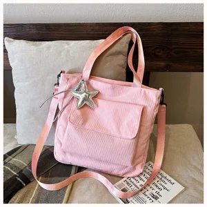 Pink corduroy tote bag detail showing large capacity, front pocket, and stylish star charm.