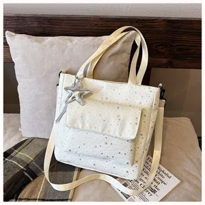 Detail shot of white star print tote bag with front pocket and star pendant for women commuting.