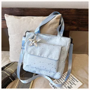 Light blue star printed tote bag detail shot featuring front pocket, straps and star pendant.