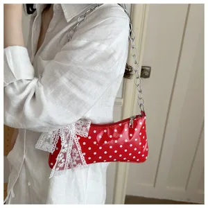 Detail van de rode schoudertas met polkadots, witte strik en zilveren ketting.