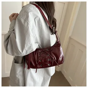 Vue détaillée du sac porté épaule en cuir verni rouge vin avec design de laçage chic.
