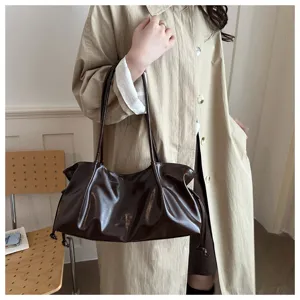 Detailed shot of dark brown patent leather shoulder baguette bag, stylish commuter hobo design.