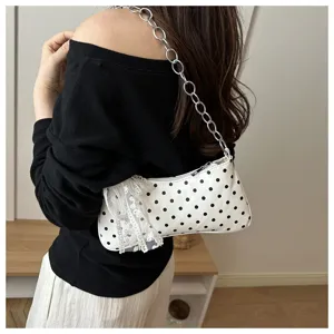 Gedetailleerd opname van een stijlvolle witte schoudertas met polkadots, ketting en mooie strik.