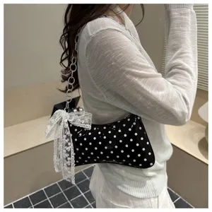 Gedetailleerd overzicht van de chique polkadot schoudertas met metalen ketting en kanten strik.