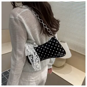 Stijlvolle zwarte lakleer schoudertas met polkadots, kettingriem en kanten strikdetail.
