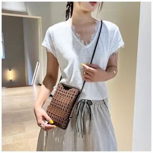 Vue rapprochée d'un élégant sac bandoulière de téléphone en cuir tressé marron foncé.