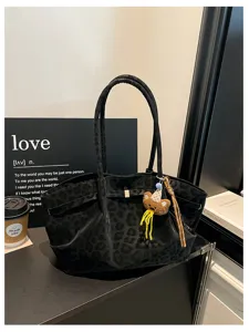 Primo piano dettagliato della borsa tote in camoscio leopardato nero con orsetto.