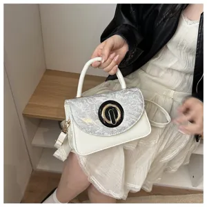 Elegante bolso de hombro blanco con solapa gris texturizada y llamativo cierre circular negro oro.