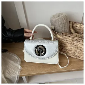 Detailed view of the stylish white and silver mini shoulder bag with elegant circular clasp.