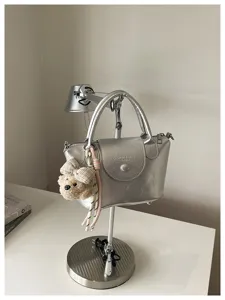 Zilveren metallic handtas detail met zachte leerstructuur en schattige ruitstrik berenhanger.
