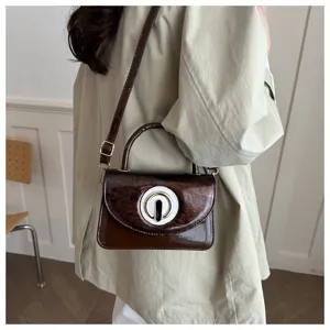 Detail view of a stylish mini patent leather crossbody bag with a chic circular lock design.