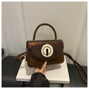 Chic brown patent leather shoulder bag with stylish round metal clasp for women daily commute.