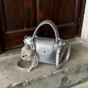 Zilveren metallische schoudertas voor dames, casual modieuze handtas met leuke berenhanger.