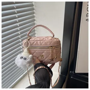 Detalle de bolso necesir acolchado rosa con elegante correa de cadena y lindo colgante de peluche.